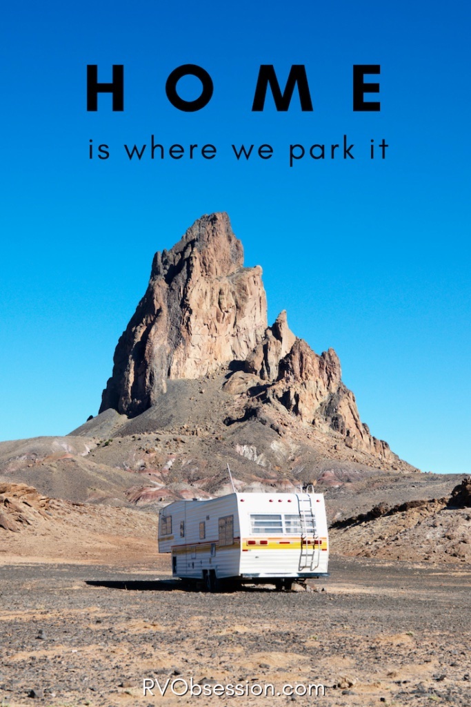 Older style RV parked in front of monument rock with text: Home is where we park it.