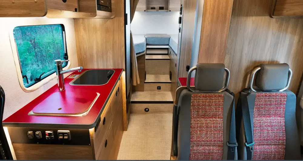 Wooden interior of small RV with a rich red kitchen countertop