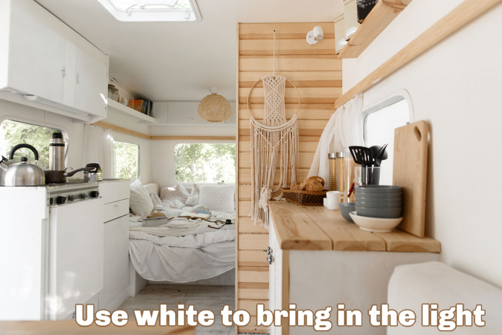 Interior of a renovated RV with text that reads: Use white to bring in the light.