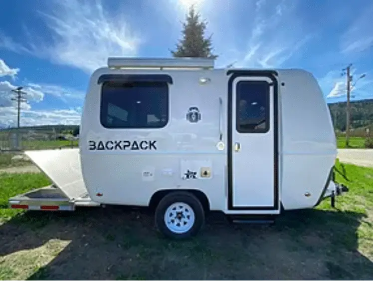 Small, white fiberglass camper with bright blue sky behind