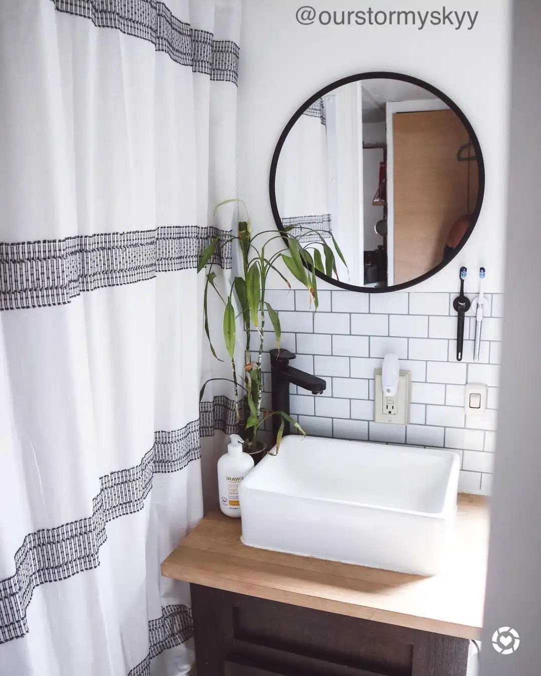 Small bathroom with vanity, wall mirror and shower curtain.