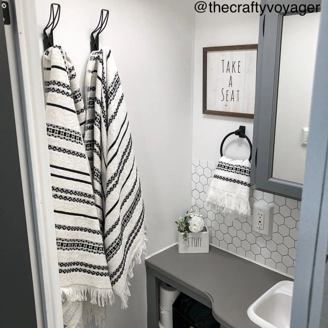 Small RV bathroom with black, white and grey decor.