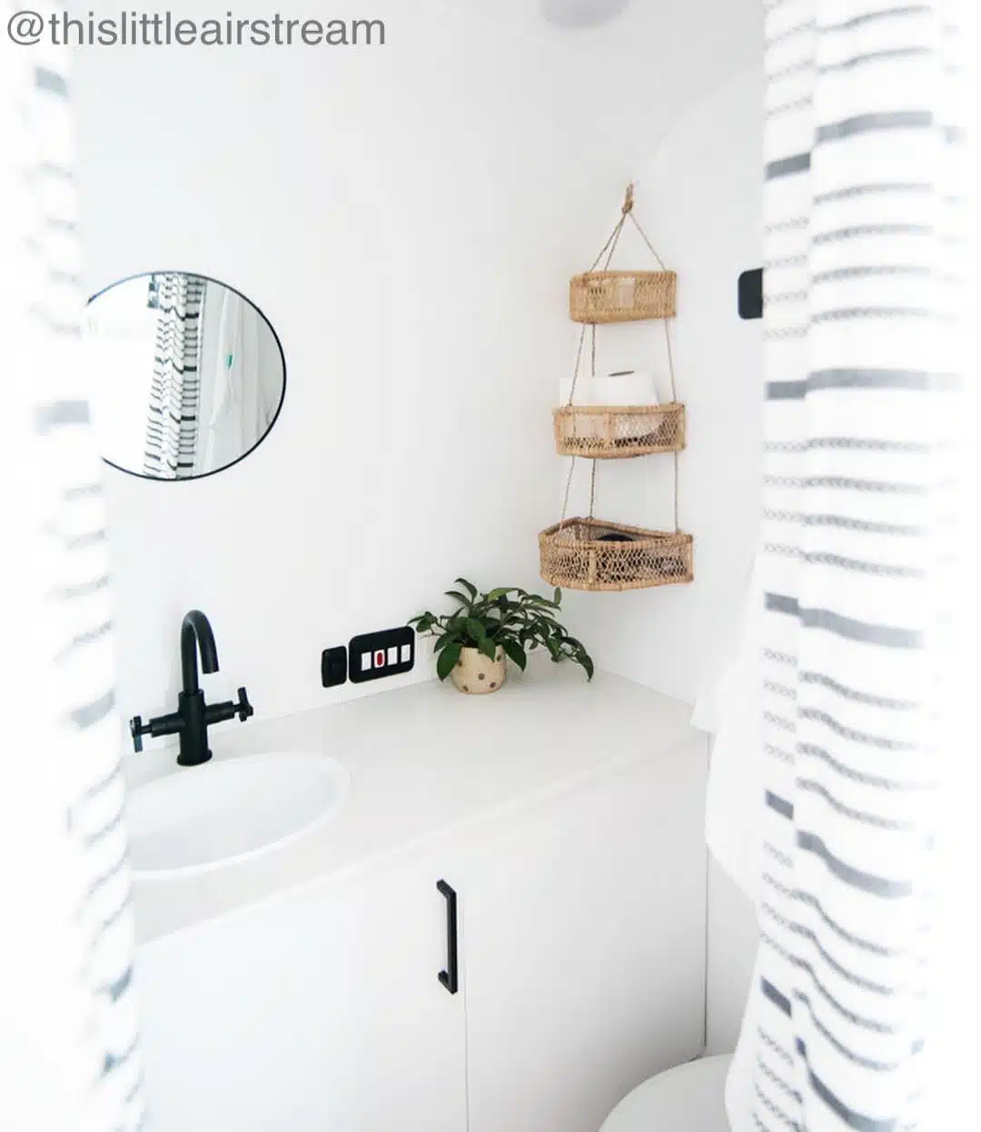 White small bathroom with hanging baskets.