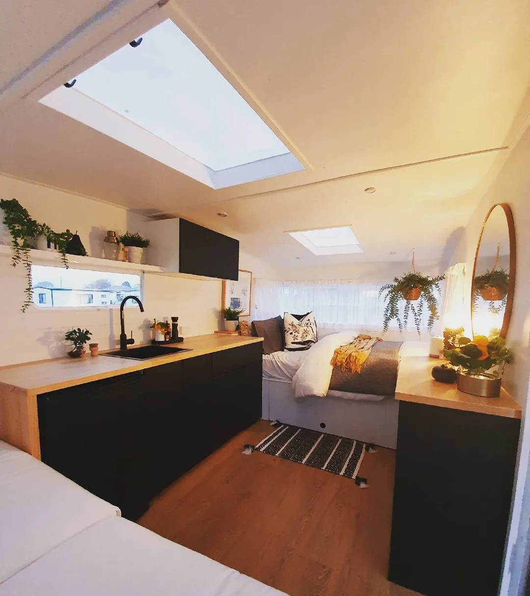 Interior view of a remodeled travel trailer showing the bed and kitchen area.