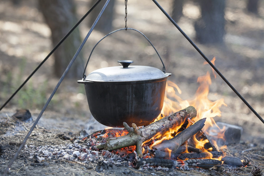 Dutch oven suspended over an open fire.