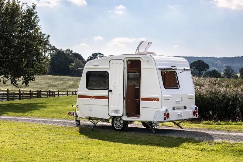 Little white caravan parked in a green field