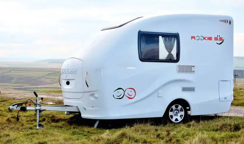 Wingamm small, white, fiberglass camper in a green field