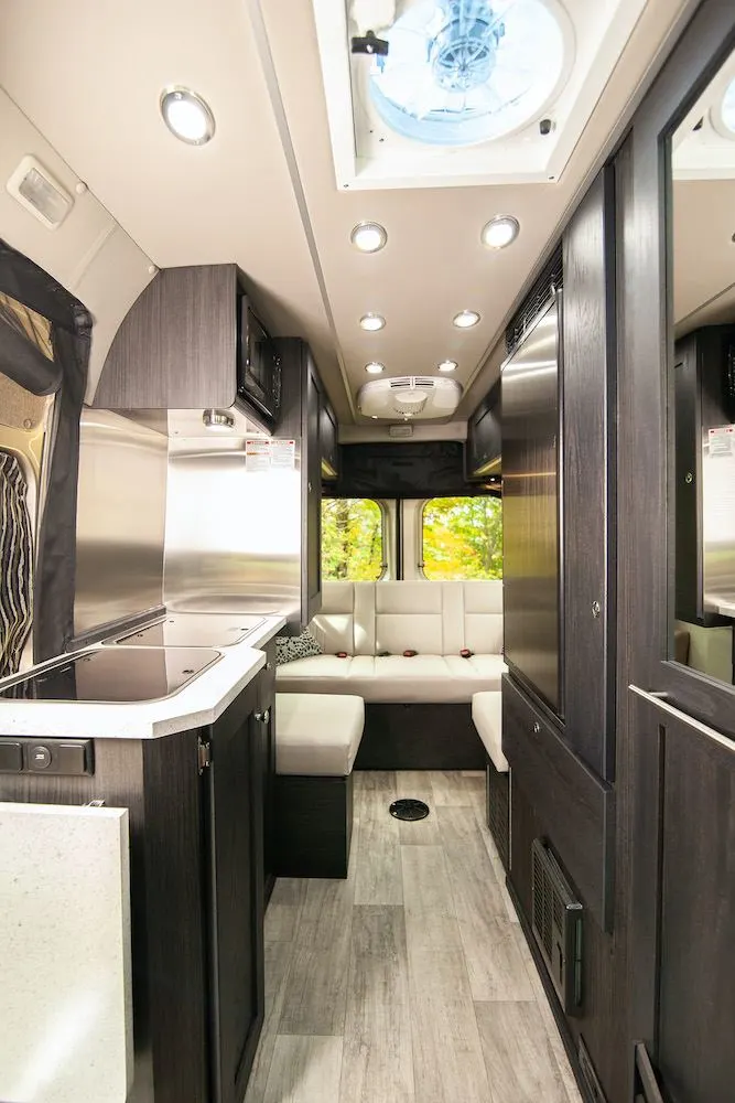 White upholstery and dark wood cabinets inside a modern camper van