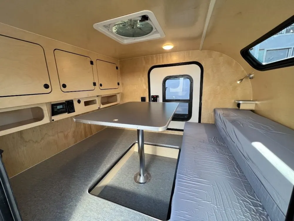 Interior view of the Steel & Steel HC camper by Aero Teardrops; showing the bed converted to a dining area.