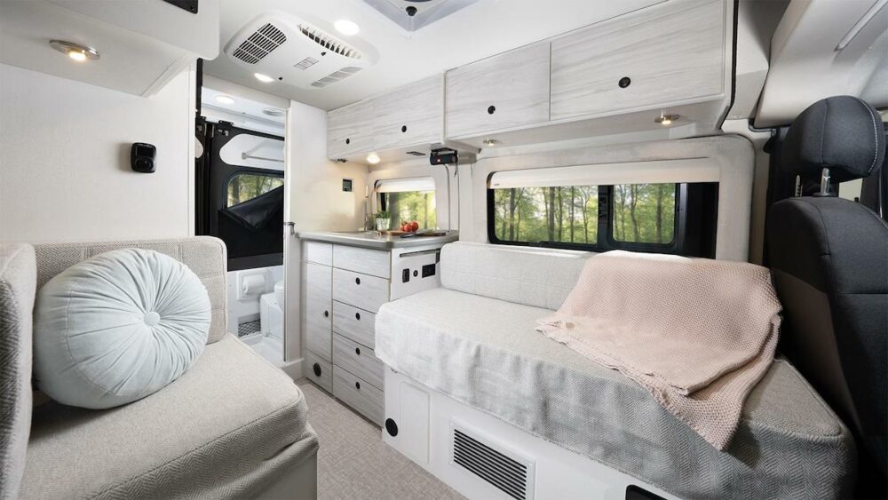 Interior view of the Jayco Comet Class B RV showing the lounge and kitchen area with light colored decor.