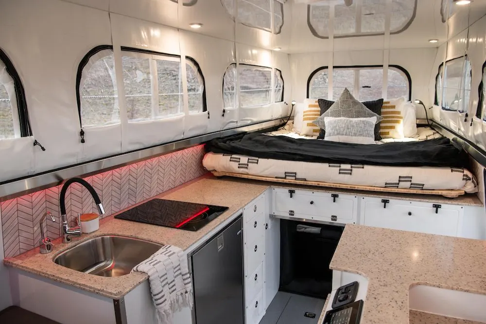 Interior view of the EarthCruiser Terranova showing the kitchen area and the bed above the cab.