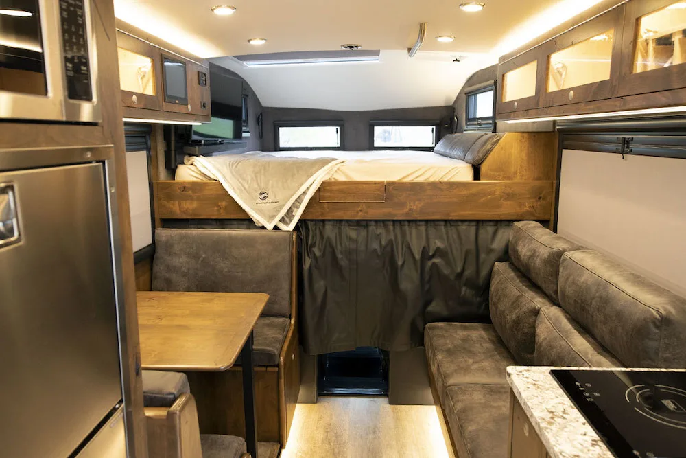Interior view of the EarthRoamer LTi Explore 4x4 RV showing the living area and the bed above the cab.