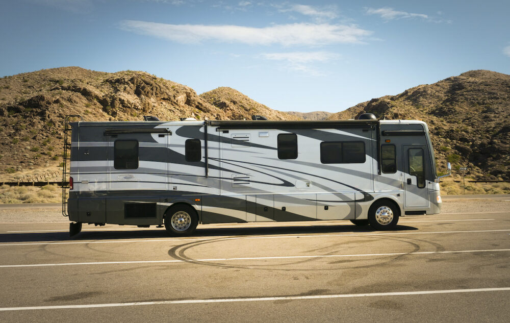 Side view of a large Class A motorhome in an empty parking lot.